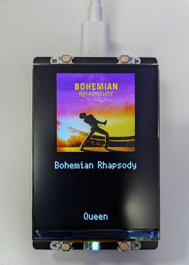 Pico with a display showing the cover art, song name and artist of Bohemian Rhapsody by Queen