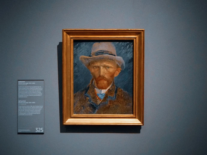 Photo of a painting depicting a self-portrait of Vincent van Gogh displayed in a beautifully lit art gallery
